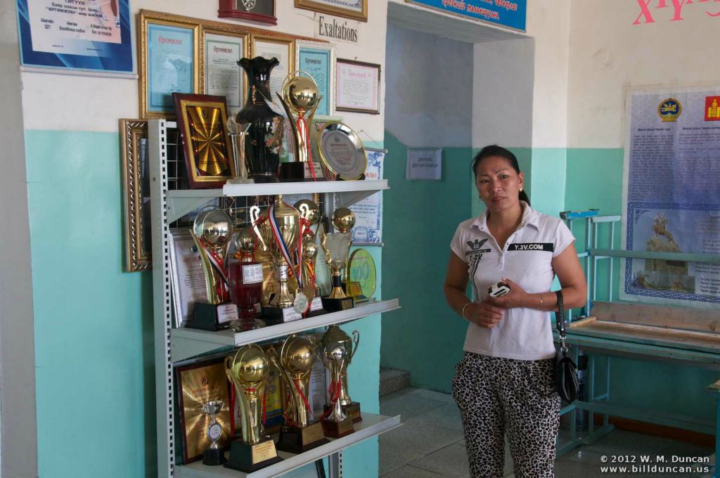 Principal shows off volleyball trophies.
